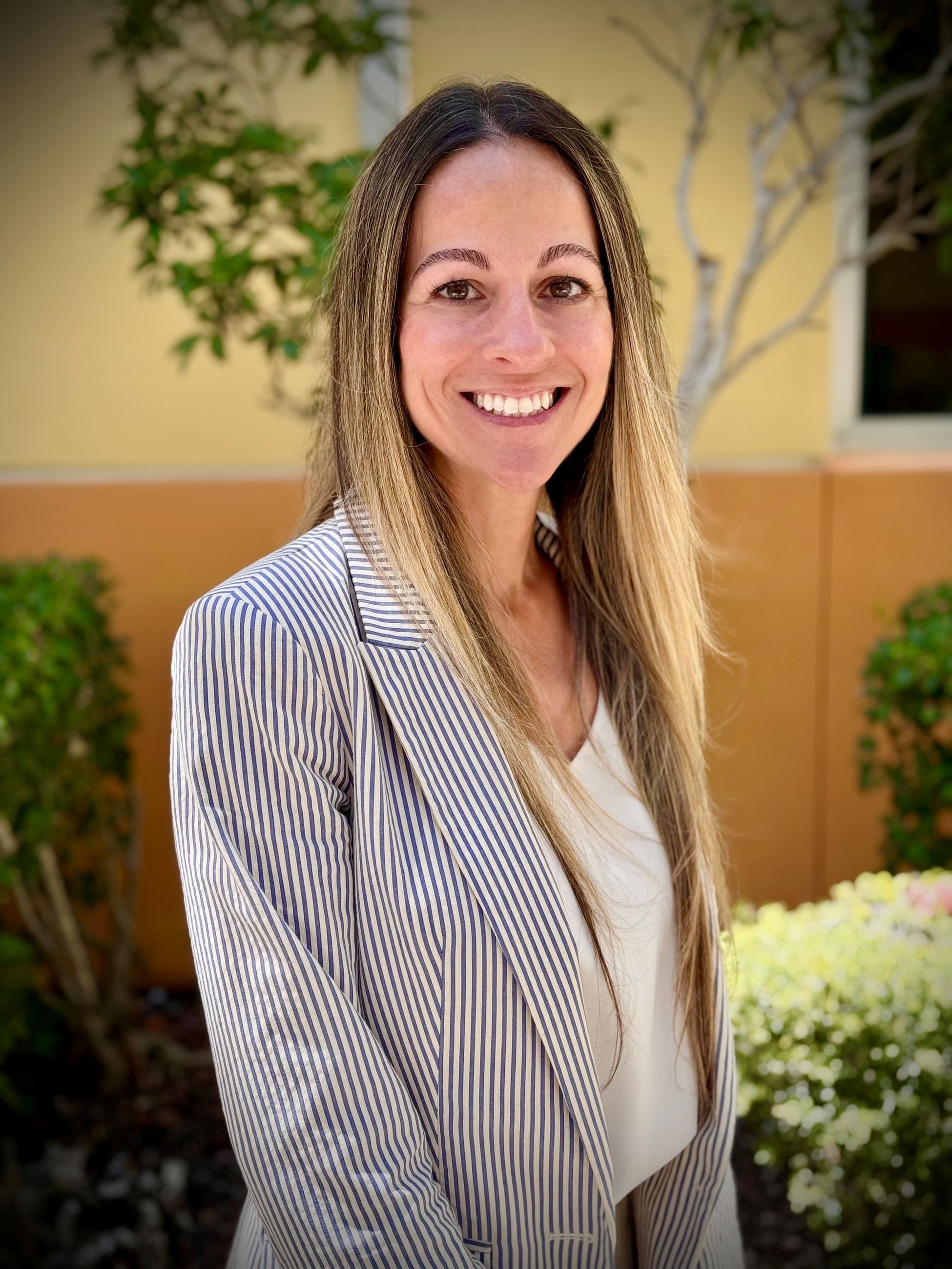 Cathy Crane headshot outside with blazer and yellow background